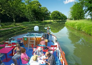 A CroisiEurope boat glides peacefully down a canal as passengers sit on deck. Photo from CroisiEurope.
